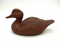Side view of vintage wooden duck decoy showing detailed carving of feathers and smooth body shape.