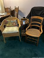 Wicker armchair, wooden cane seat chair, and rattan plant stand arranged together showing overall lot contents.