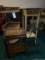 Photo showing the four items: three accent tables including wicker corner shelf, wooden side table, and square wooden accent table, and black metal two-tier plant stand.