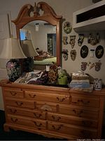 Full view of dresser with mirror showing drawer layout, metal handles, and top surface with various items.