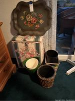 Clothes hamper, five wastebaskets, and large decorative tray grouped on floor near dresser and window.