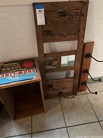 Photo of primitive wooden hat rack, wall hook rack, and apple crate seen on floor