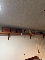 Long wall-mounted wooden shelf holding 9 items including 3 wooden boxes and various decorative pieces.