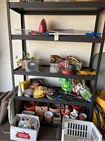 Garage metal shelf with gardening, tool, and miscellaneous items including iron and candles