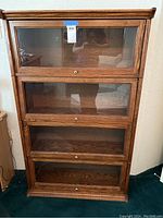 Front view of the oak lawyer's bookcase showing four glass front compartments with round knobs.