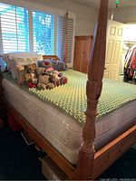 Queen size four poster knotty pine wood bedframe with mattress, boxspring, pillows and stuffed animals on bed