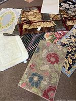 Multiple rugs shown laid out on floor, displaying various patterns including florals and geometric designs.