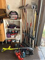 Overall view of shelf with paint cans, garden tools, and electric hand tools