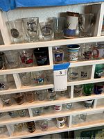 Shelves filled with various shot glasses featuring different city names, landmarks and logos of places