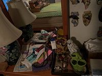 Dresser top with various items including colorful Disney bag, owl figurines, green owl container, small linens, and other small decorative items