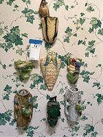 Seven ceramic wall vases arranged on wallpapered wall