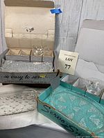 Two unopened vintage glass luncheon serving sets in original boxes, one with grape cluster design, the other with bubble/hobnail pattern. Plates and cups arranged in front.