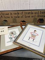 Two framed prints and the wooden primitive sign displayed together showing titles and scene details.