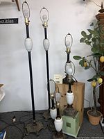 Full view of 6 lamps in group showing four table lamps and two taller floor lamps with white hobnail ceramic bodies and metal ornate bases