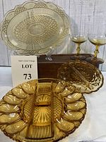 Photo showing the full lot with several amber glass pieces including egg plate, serving platter, split dish and two champagne glasses