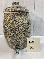 Full front view of vintage Roseville splatterware crock beverage dispenser with attached spout and lid, next to lot number sign.