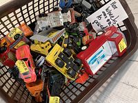 Brown basket filled with numerous Hot Wheels and other toy cars, various colors and conditions