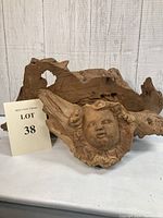 Driftwood sculpture with cherub face and lot sign.