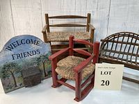Photo showing a vintage Welcome Friends sign with 3D house and three small handcrafted wooden doll furniture pieces: two natural wood benches and one red rocking chair with woven seats.