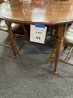 Full view of round wooden Hitchcock table showing spindle legs and crossbars.