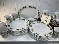 Photo shows entire set including plates, cups, saucers, large platter, creamer, and sugar bowl arranged on a white surface with a label Lot 49