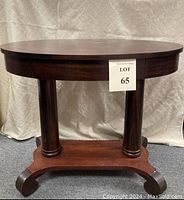 Full front view of the antique mahogany veneer oval writing desk showing the top surface, double column base, and lower shelf.
