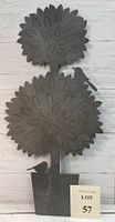 Full view of dark metal wall art of stylized boxwood tree with two round leaf clusters, a trunk, and a pot base with bird silhouettes.