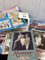 Photo showing the eight vintage magazines, including McCall Needlework & Craft magazine with blue cover and multiple Reminisce magazines with nostalgic vintage photo covers.