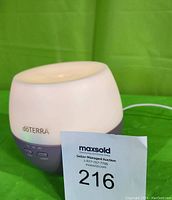 Photo of white and lavender doTERRA Petal diffuser with diffuser controls visible, next to auction card.