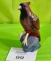 Front left angled view of the bird figurine showing detailed paintwork and rock base