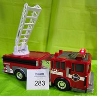 Front and side view of the red Hasbro Tonka fire truck toy with working lights and ladder raised.