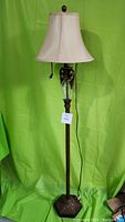 Full view of vintage floor lamp showing brass/bronze finish, tall structure with fabric lampshade and hanging pull chain.