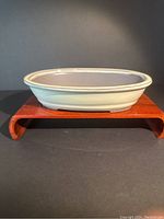 Front side view of the beige bonsai planter on a wooden stand for display