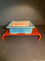 Photo of blue glazed bonsai planter on wooden stand, showing front angle and interior wear.