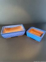 Two rectangular bonsai planters shown side by side with cobalt blue glaze on the outside and bare terracotta inside.