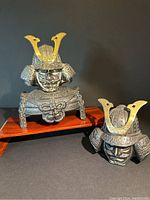 Front view of the two samurai helmet bottle toppers showing one with shoulder armor and one without.