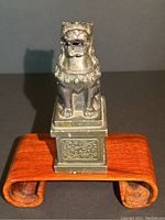 Front view of vintage bronze Foo dog statue on carved pedestal