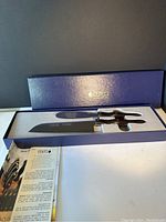 Two Cutco knives in blue display box with instruction booklet below, branded inside lid.