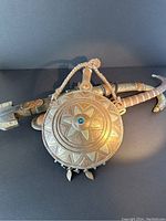 Three items: two curved sheath cutting utensils and one decorative copper and steel flask with a blue stone.