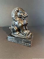 Front and side view of the black carved stone Foo dog statue, showing detailed carving and glossy finish.