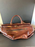 Front view of the brown vintage Saga leather bag showing outer zippered pocket and buckle closure.