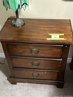 Front view of the solid wood side stand showing three drawers with metal ring pull handles.