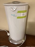 Full view of the white electric towel warmer showing the unit standing on a flat surface, power cord visible.