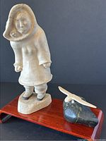 Full view of whale bone Inuit figure and bone owl on wooden platform