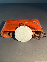 Front view of white jade pendant showing dragon and phoenix carved details.