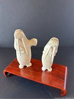 Two walrus figurines on a wood stand showing full body front view.