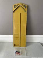 Full view of yellow Rebound game board with marbles and string in a plastic bag at the bottom