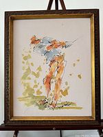 Full view of the framed watercolour painting showing the golfer in mid-swing with frame and easel.