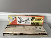 Photo showing the original colorful box of the 'Miss World's Fair' radio controlled model airplane alongside detailed assembly plans.