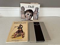 Three books displayed together: 'The Clans of the Scottish Highlands', 'The Doll', and 'MGM'